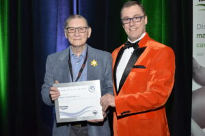 An elderly gentleman (Peter Stachnyk) receives a 45th anniversary certificate from a younger man (MTAM president Paul Kohlmeier).